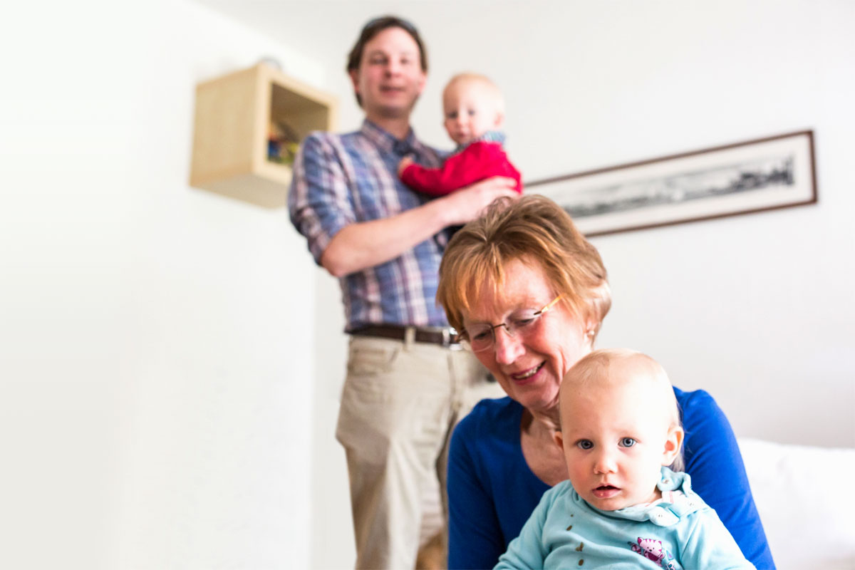 Vater mit einer Ehrenamtlichem und Kind auf dem Arm